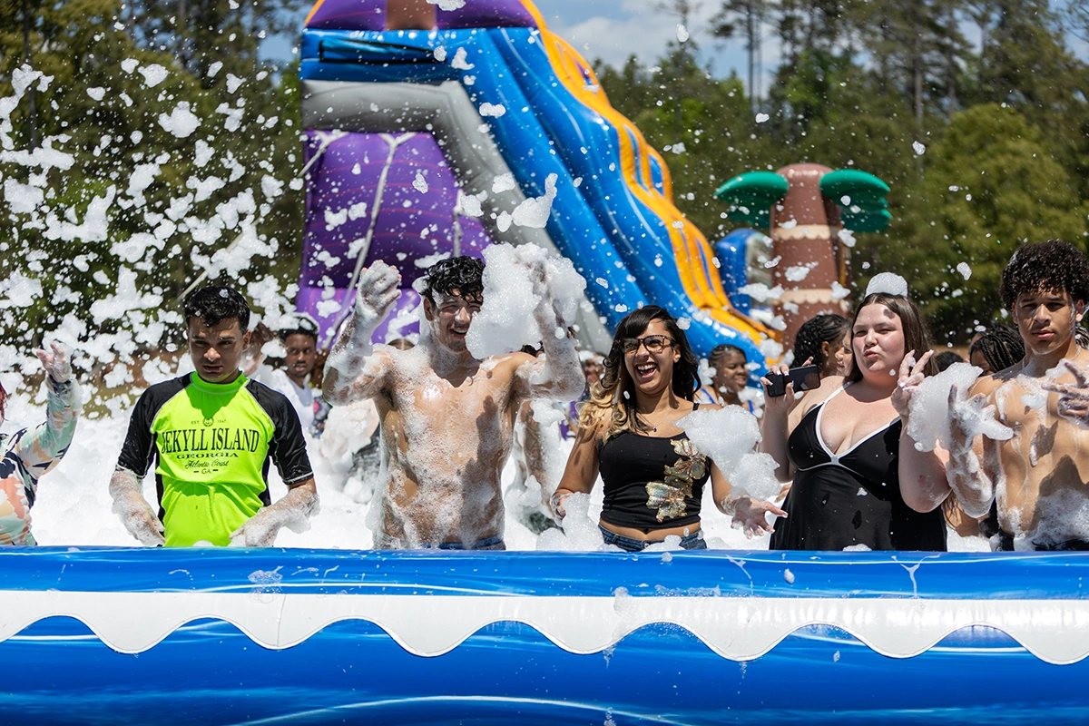 group of students in bathing suits splashing bubbles outside