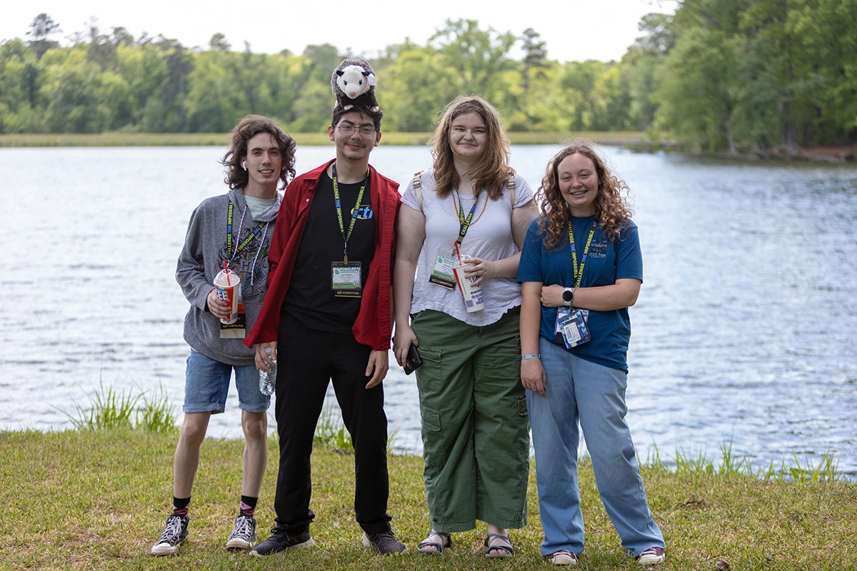 Four students posed in front of a lake